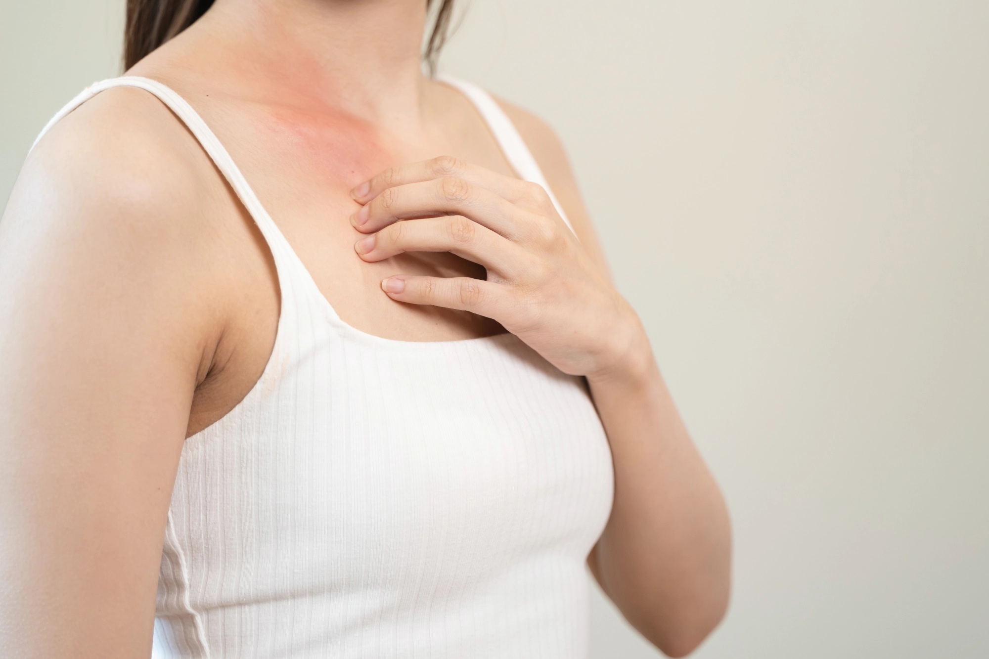 A close-up of a person experiencing skin irritation on their chest, illustrating common symptoms of eczema or psoriasis